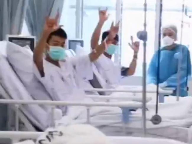 The rescued boys smile and wave at their parents through a glass partition. Picture: Twitter.