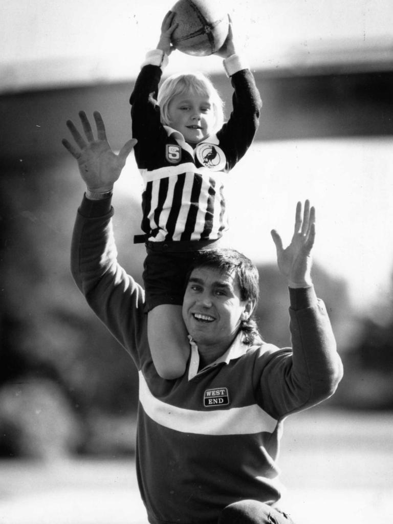 Erin Phillips, 5, takes a mark over dad Greg Phillips 1990. Picture: Phil Hillyard