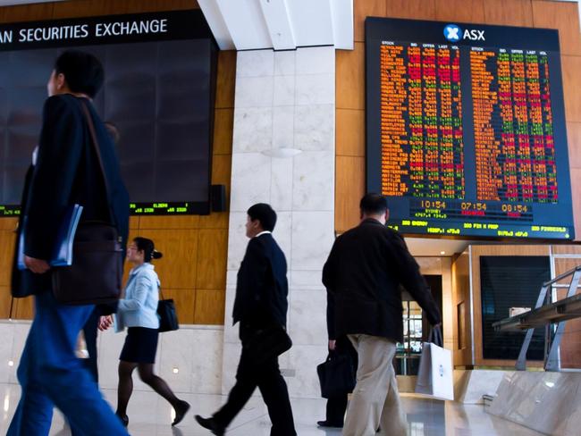 People walk in front of an electronic board which displays stock prices inside the Australia Securities Exchange (ASX Ltd.), building in Sydney, Australia, on Monday, Nov. 1, 2010. Singapore Exchange Ltd.'s A$8.1 billion ($8 billion) bid for ASX Ltd. will be vetted by Australia's Foreign Investment Review Board before approval, Prime Minister Julia Gillard said in an interview with the Australian Broadcasting Corp. Photographer: Ian Waldie/Bloomberg