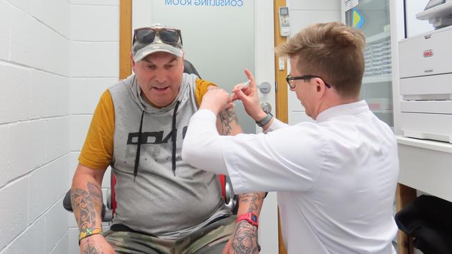 Ulverstone speedway racer Darren Saunders gets his first Moderna vaccine at Penguin Pharmacy from pharmacist Joe Malley.