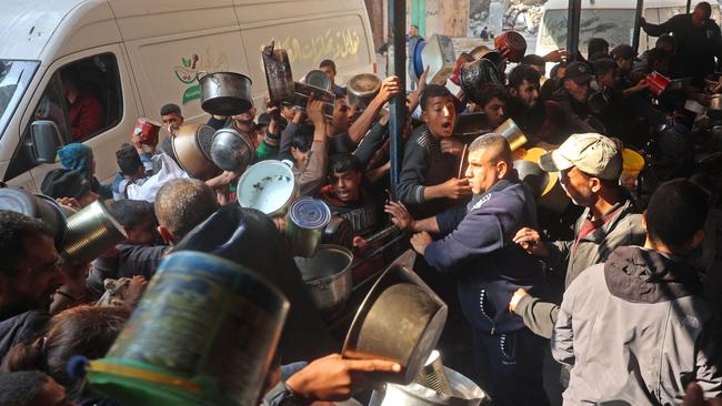 Palestinians gather to receive aid food being distributed along the roadside at the Nuseirat refugee camp on January 11. Picture: Eyad Baba/AFP