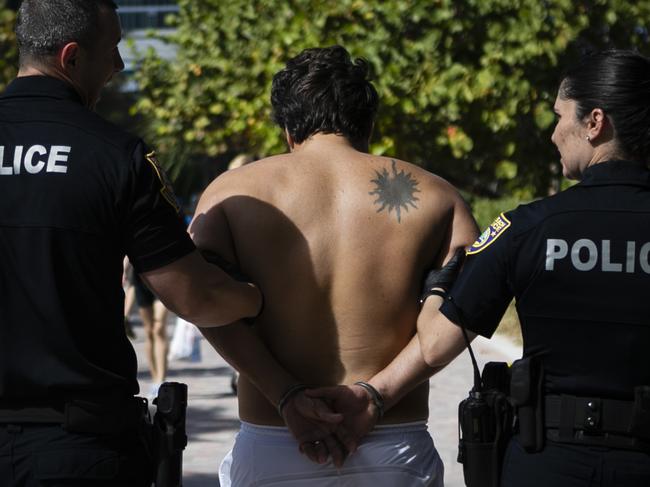 Got the message yet? Police detain a man who went onto a closed beach in Florida. Picture: AFP