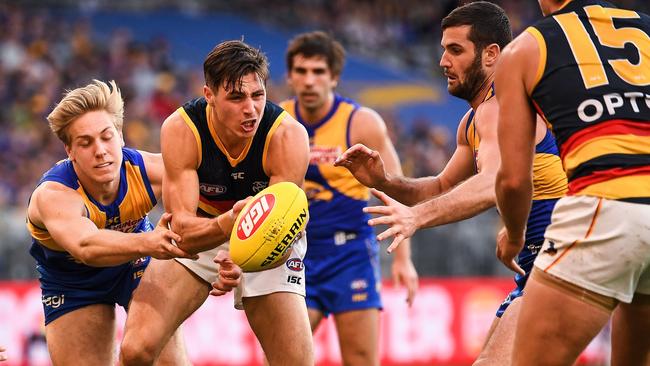 Jake Kelly fires out a handpass in front of West Coast forwards Oscar Allen and Jack Darling. Picture: Daniel Carson/AFL Photos.