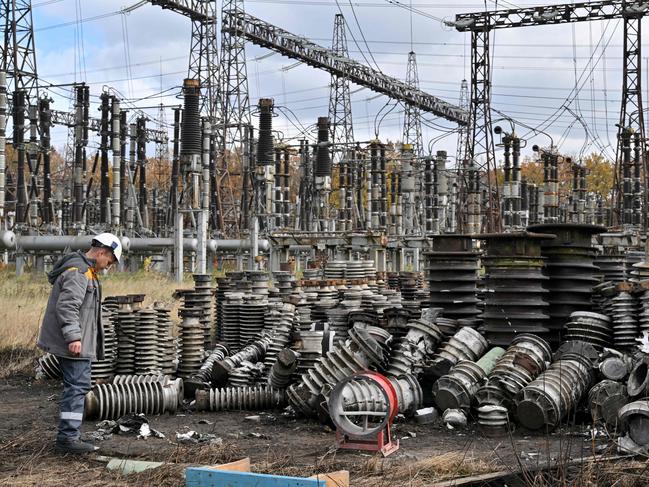 (FILES) In this file photo taken on October 27, 2022, a worker examines damage as he repairs  power line equipment destroyed after a missile strike on a power plant, in an undisclosed location of Ukraine, amid the Russian invasion of Ukraine. - Russian drones and missile strikes led to power cuts in "hundreds of settlements" across seven Ukrainian regions on October 31, Prime Minister Denys Shmyhal said. (Photo by Sergei SUPINSKY / AFP)