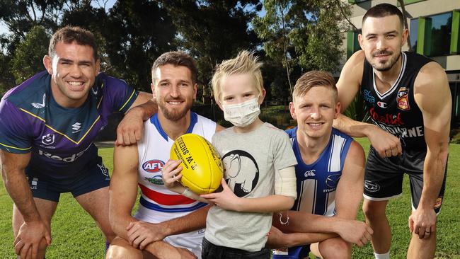 Seven-year-old Ralph Rodgers with Melbourne Storm co-captain Dale Finucane, Western Bulldogs skipper Marcus Bontempelli, North Melbourne captain Jack Ziebell and Melbourne United captain Chris Goulding to promote the Good Friday Appeal. Picture: Michael Klein