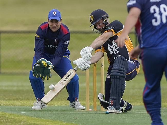 Main Ridge opener Michael Holmes smashes a cover drive as Long Island keeper Michael Chaplin looks on.