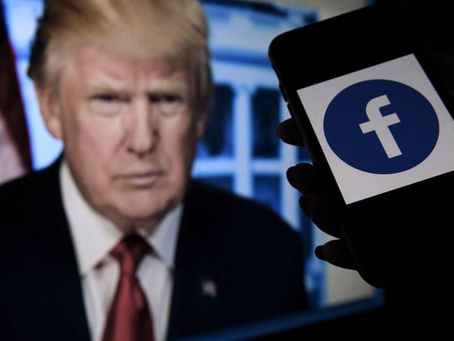 In this photo illustration, a phone screen displays a Facebook logo with the official portrait of former US President Donald Trump on the background, on May 4, 2021, in Arlington, Virginia. - Facebook's independent oversight board was set for a momentous decision on the platform's ban of former US president Donald Trump, as debate swirls on the role of social media in curbing hateful and abusive speech while controlling political discourse. (Photo by Olivier DOULIERY / AFP)