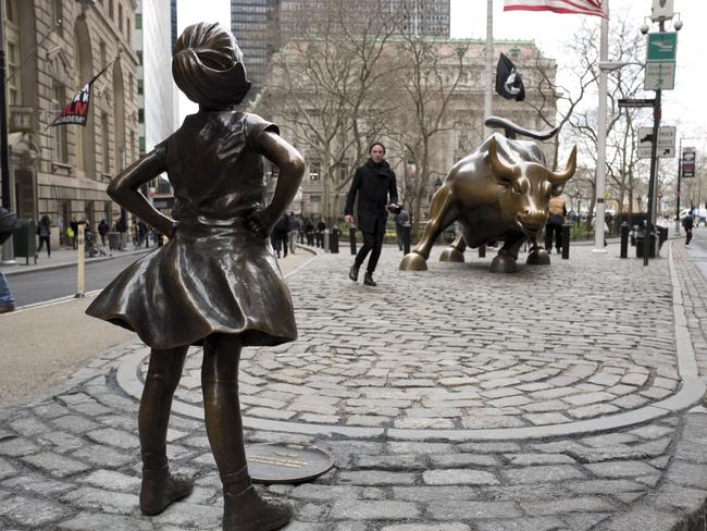 A statue titled "Fearless Girl" faces the Wall Street bull, Wednesday, March 8, 2017, in New York. A big investment firm, State Street Global Advisors, put the statue there to highlight International Women's Day. The work by artist Kristen Visbal. (AP Photo/Mark Lennihan)