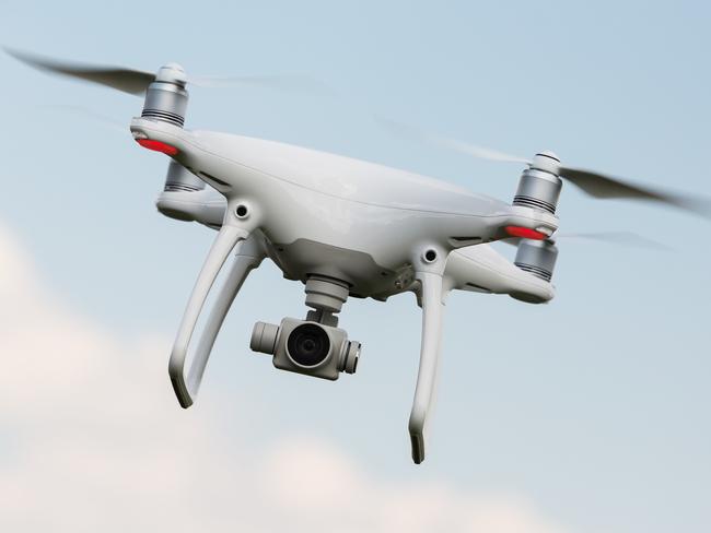 White drone, quadrocopter with photo camera flying in the blue sky. Concept,