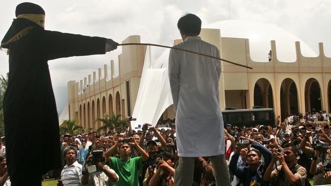 A Sharia law official whips a man convicted of unlawful contact between unmarried man and woman during a public caning in Jantho, Aceh province, Indonesia.