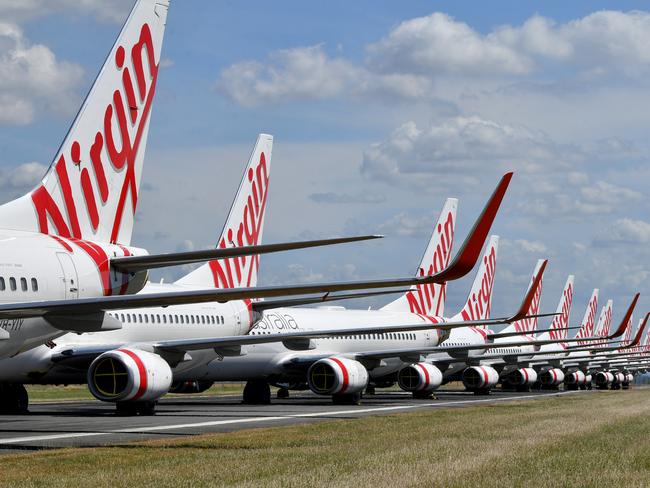 Grounded Virgin Australia aircraft are seen parked at Brisbane Airport in Brisbane, Tuesday, April 7, 2020. Brisbane Airport Corporation (BAC) is working with airlines by accommodating up to 100 grounded aircraft free of charge in response to government-mandated travel restrictions that have grounded a significant proportion of Australia's airline fleet because of the Coronavirus (COVID-19). (AAP Image/Darren England) NO ARCHIVING