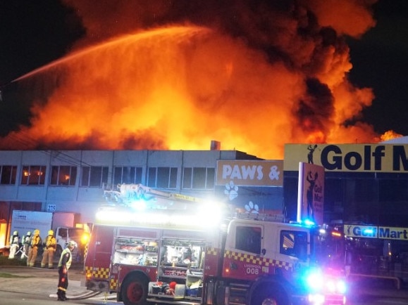 Aerial crews work to contain the six-alarm blaze, using ladder platforms to stop the fire from spreading to nearby businesses. Picture: Sydney Emergency