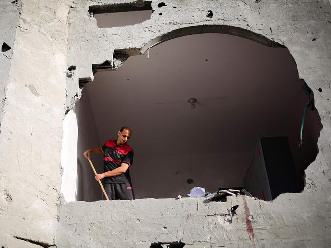 Blood stains are visible on the wall as a man sweeps rubble in a building hit by Israeli bombing in Rafah in the southern Gaza Strip. Picture: AFP