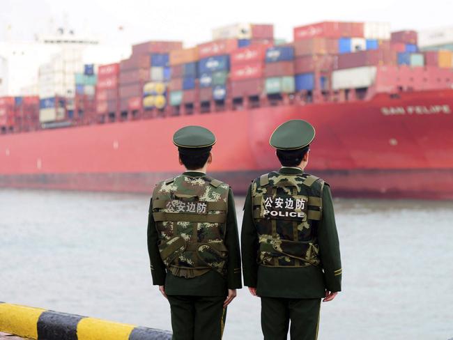 FILE - In this March 8, 2018, file photo, Chinese border police officers watch the arrival of a container ship at a port in Qingdao in eastern China's Shandong province. China announced a list of U.S. goods including pork, apples and steel pipe on Friday, March 23, 2018, that it said may be hit with higher import duties in response to President Donald Trump's tariff hike on steel and aluminum. (Chinatopix via AP, File)