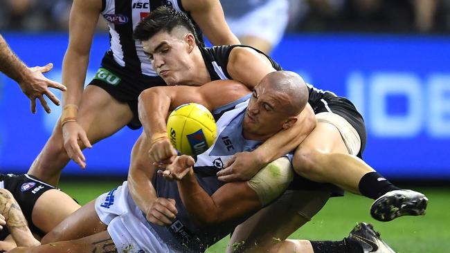 Sam Powell-Pepper of the Power handballs while being tackled by Brayden Maynard of the Magpies. Picture: Quinn Rooney/Getty Images