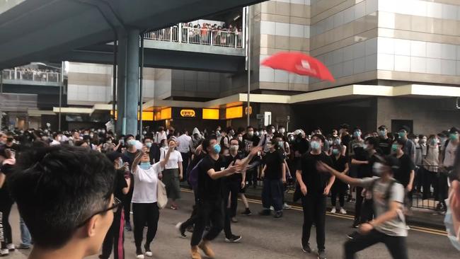 A protester catches an umbrella dropped from a Hong Kong walkway. Picture: Jillian Melchior / The Wall Street Journal