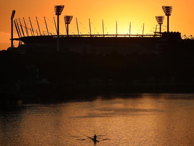 Rower on the Yarra as the sun rises behind the MCG. Picture: Nicole Garmston