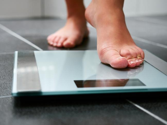 Weighty debate: Ozempic Female bare feet with weight scale in the bathroom, scales generic