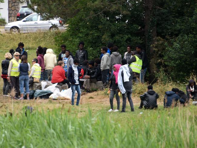 Migrants wait on a field near the ring road leading to the port of Calais in northern France. Picture: AFP