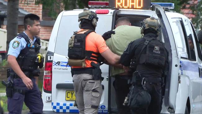 Police take a man into custody outside a home in Belmore. Picture: News Media Network