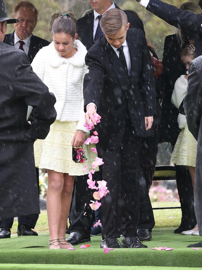 The showbiz legend’s grandchildren scatter rose petals on his coffin. Picture: David Caird