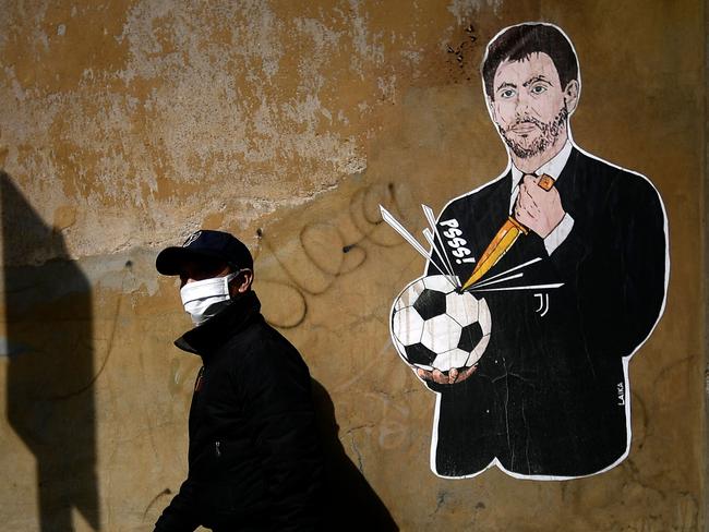 A man walks past a grafiti entitled 