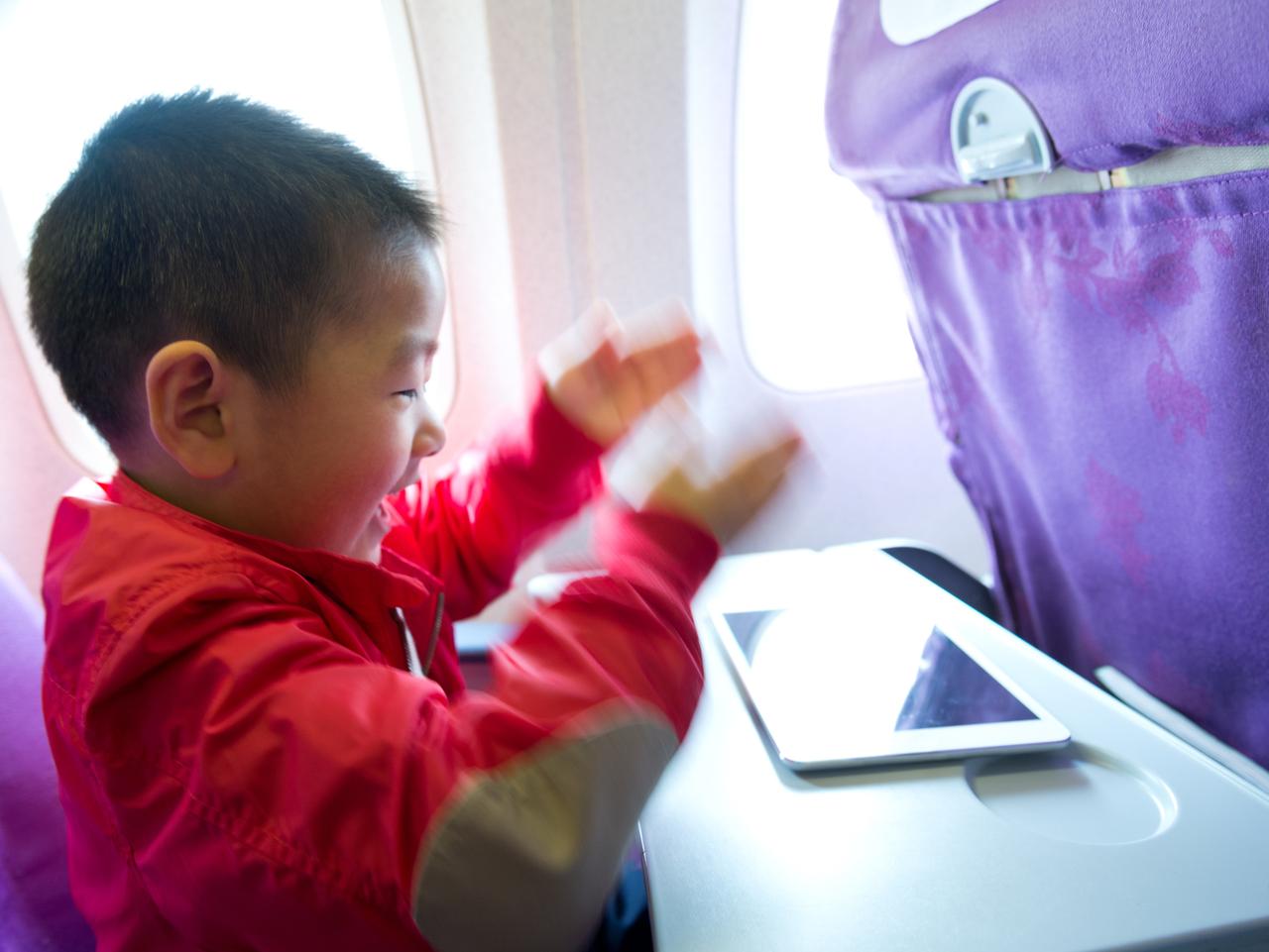 Little boy playing with a tablet computer in plane