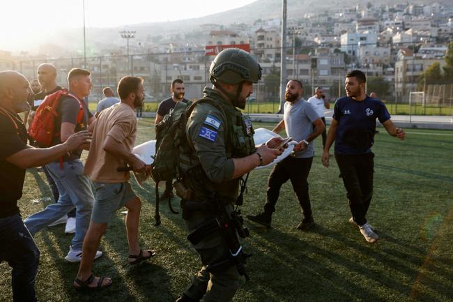 Israeli paramedics carry away the wounded for treatment after a rocket fired from Lebanon hits a football pitch in the town of Majdal Shams in the annexed Golan Heights