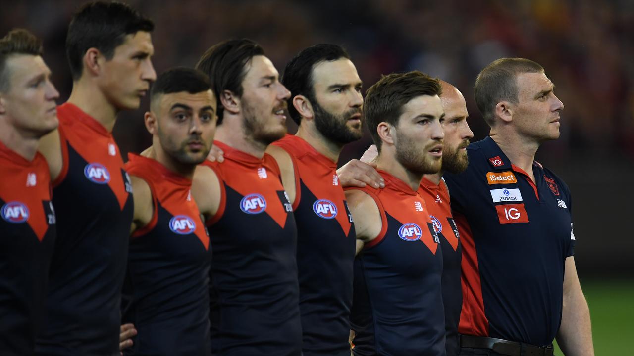 Demons coach Simon Goodwin (right) is seen alongside his players during the national anthem. (AAP Image/Julian Smith)