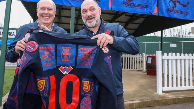 Norwood legend and Hall of Fame member Roger Woodcock (left), holds a duffel coat with his number 10 on it, alongside another former Redleg, Brenton Klaebe, at the Parade on Sunday after the goalkicking great was honoured with the goals at the northern end of the ground named after him. Picture: Russell Millard.