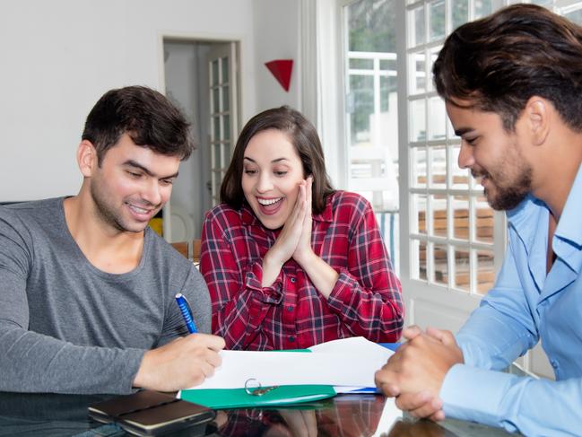 Excited couple signing contract for own house indoor with real estate agent