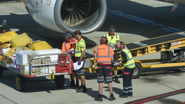 Adelaide Airport baggage handlers deal with luggage on Thursday while appearing to disregard social distancing. Picture: Roy VanDerVegt