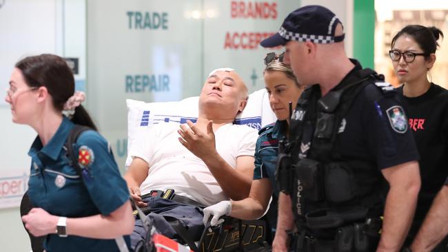 An injured man is taken by ambulance and police from Australia Fair shopping centre. Picture: Nigel Hallett