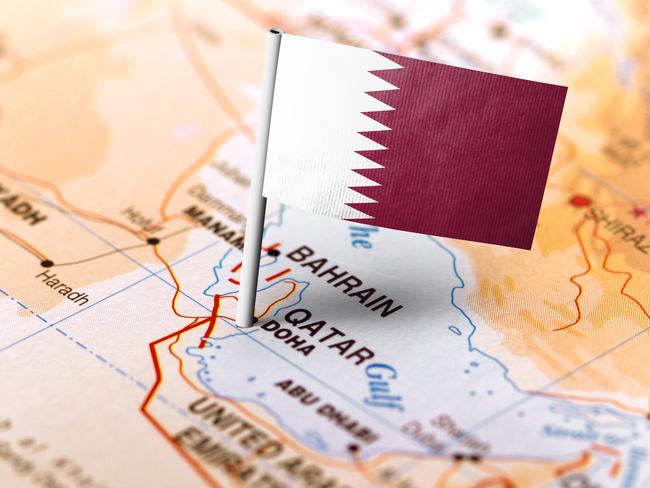 The flag of Qatar pinned on the map. Horizontal orientation. Macro photography.