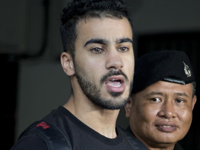 Bahraini football player Hakeem al-Araibi, left, answers questions from the waiting journalists as he is brought in to a court in Bangkok, Thailand, Tuesday, Dec. 11, 2018. A Thai court has ruled that the soccer player who holds refugee status in Australia can be held for 60 days pending the completion of an extradition request by Bahrain, the homeland he fled four years ago on account of alleged political persecution. (AP Photo/Gemunu Amarasinghe)