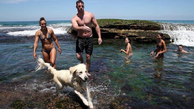 Sarah Kelly and Ross Dunne revel in the chance to take Paris the golden retriever for a dip at Bronte Beach rockpools in Sydney’s east on Sunday. Picture: Jane Dempster