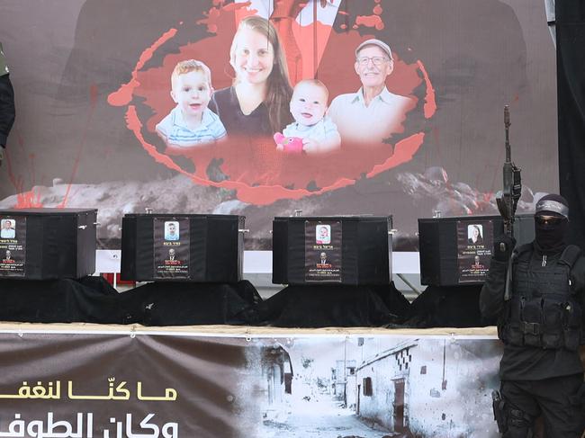 Armed Palestinian militants stand next to the coffins on stage before handing over the bodies of four Israeli hostages to the Red Cross in Khan Yunis in the southern Gaza on February 20, 2025. Hamas handed over on February 20 coffins believed to contain the bodies of four Israeli hostages, including those of the Bibas family who became symbols of the ordeal that has gripped Israel since the Gaza war began. The transfer of the bodies is the first by Hamas since its October 7, 2023 attack on Israel triggered the war, and is taking place under a fragile ceasefire that has seen living hostages exchanged for Palestinians held in Israeli prisons. (Photo by Omar AL-QATTAA / AFP)