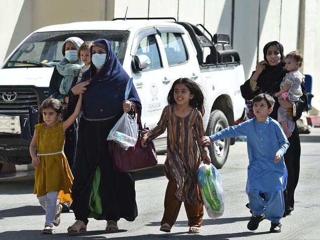 Afghan women with children, hoping to leave Afghanistan, walk through the main entrance gate of Kabul airport. Picture: AFP