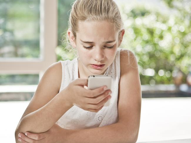 A young girl is worried, she is looking at her phone.