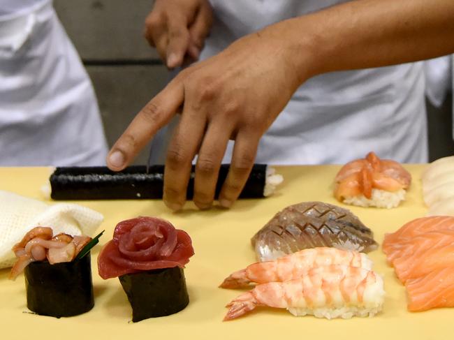 (FILES) A file picture taken on August 18, 2016 shows a foreign sushi chef making sushi at the World Sushi Cup Japan 2016 in Tokyo. A Japanese sushi chain is being accused of 'wasabi terrorism' on October 3, 2016 after it admitted to heaping excess dollops of the pungent root into foreign customers' food. / AFP PHOTO / TORU YAMANAKA