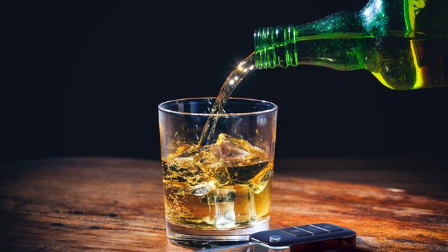 Drinking and driving concept. Car key and whiskey glass and bottle on a wooden bar counter background. 3d illustration. Picture: iStock/Rawf8