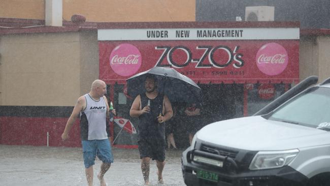 Major flooding in Currumbin Creek rd at Currumbin. Ben Freriechs and Dylan Coleman from Sel's autos watch the crisis unfold with a beer. Picture Glenn Hampson