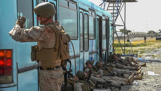 US soldiers rest as Afghan people wait to leave Kabul after a stunningly swift end to Afghanistan's 20-year war. Picture: AFP