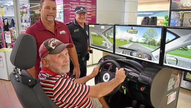 TEST DRIVE: Alan Weeton tries out the driving simulator for Road Safety Week with Greg Caletti, from the Maranoa PCYC, and Senior Constable Dale Kenna, of Roma Police. Picture: Jorja McDonnell