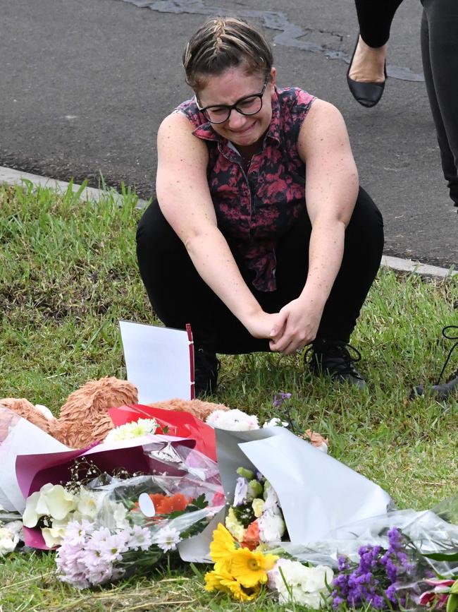 A woman cries at the site where Ryan Teasdale was swept into a drain at Unanderra.