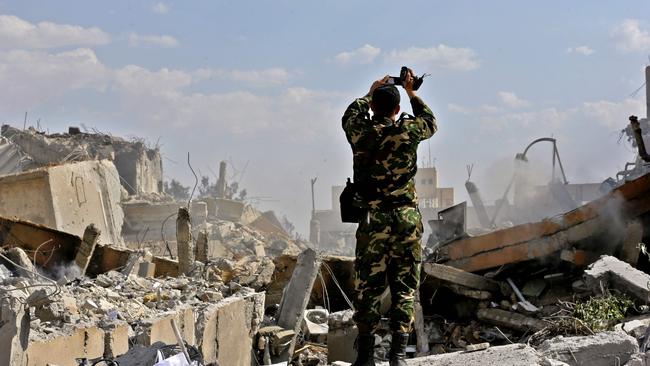 A Syrian soldier inspects rubble in the Barzeh district, north of Damascus, after the raid. Picture: AFP