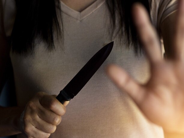 Woman holding a knife in hand while defending herself from attacks. Photo: iStock