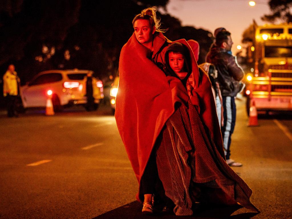 A mother and her son walk from the scene of a school bus crash in Eyensbury. Children were left with severe injuries, some requiring amputation. Picture: Jake Nowakowski