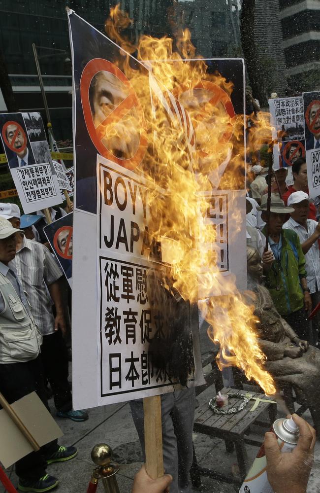 A South Korean protester ... burns defaced images of Japanese Prime Minister Shinzo Abe during a rally denouncing his statement to mark the 70th anniversary of the end of WWII. Picture: AP