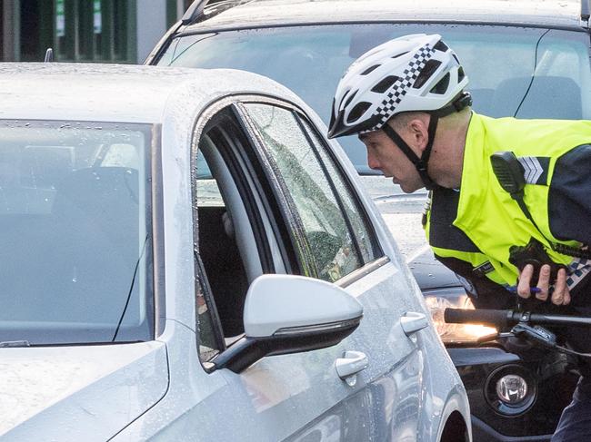 Bike patrol - Victoria Police in Richmond are using cycling police to catch people on their mobile phone while driving. They also patrol laneways where drug dealing has been an issue. Sergeant Peter Guerin books a driver for using her phone while on Swan Street. Picture: Jake Nowakowski